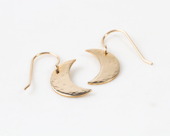 Image shows close up of the 14 karat gold fill celestial sisterhood moon earrings. Easy to wear, these earrings are made from elevated materials and can be worn every day without change. A delicate hand hammer texture mimics the surface of the moon.