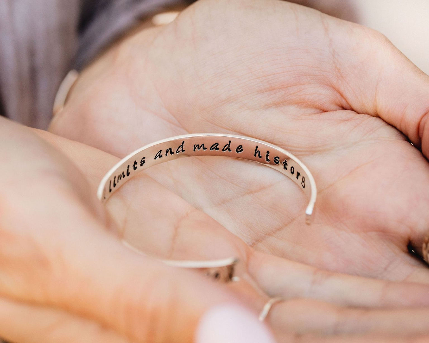 A person's hand holding a bracelet with the text "I love you" engraved on it.