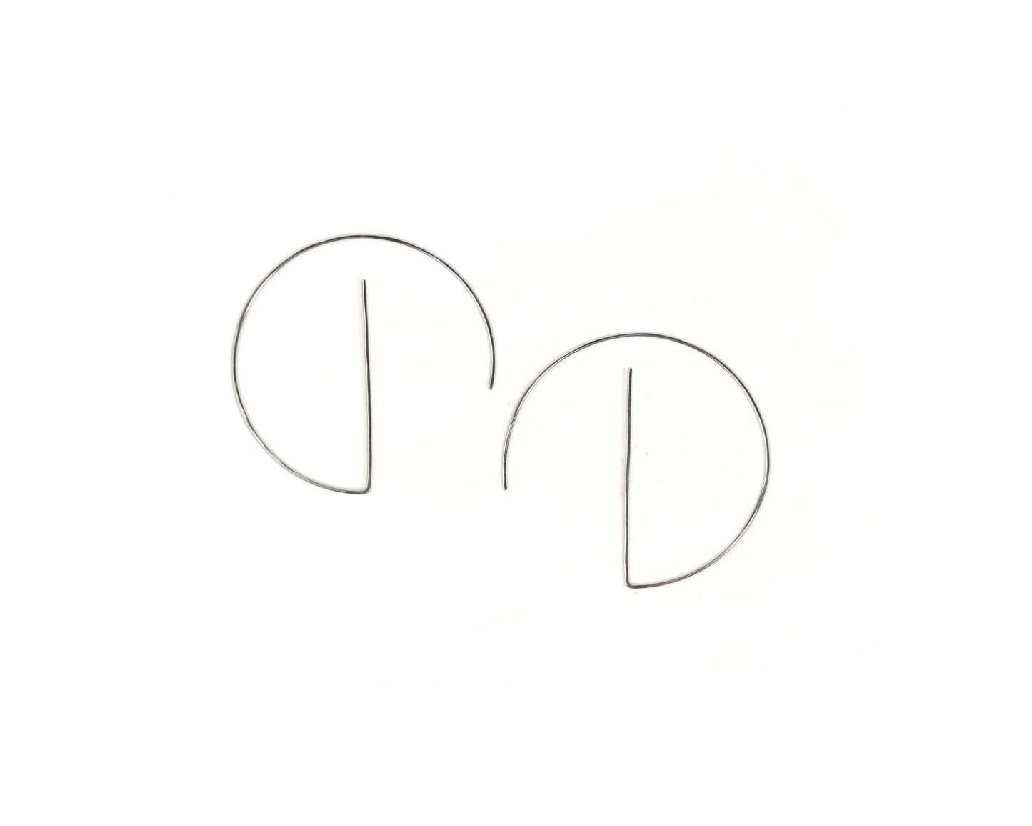 A pair of silver earrings with a unique design, featuring two circular components connected by a thin wire.