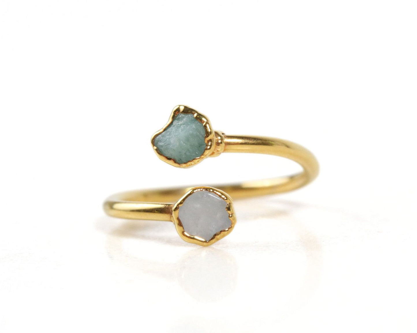 A gold ring with two gemstone stones, one green and one gray, set in a twisted design.