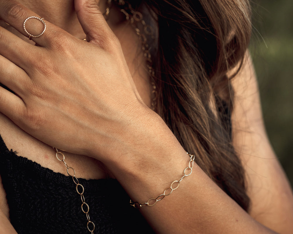 Model is wearing a single oval link 14 karat gold filled bracelet. It glints and gleams and catches the light beautifully. Each oval is linked together. Great layered or stand alone. Perfect gift for her or gift for self. High quality design.