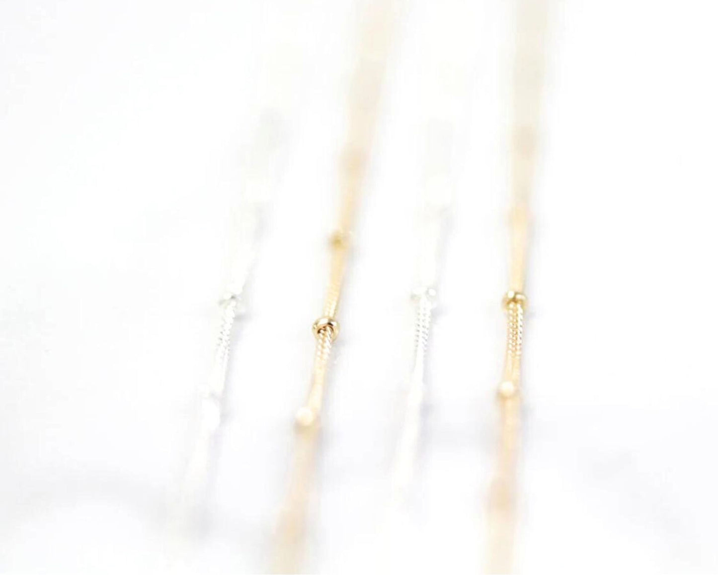 A close-up view of a delicate chain necklace with multiple strands of gold and white beads.