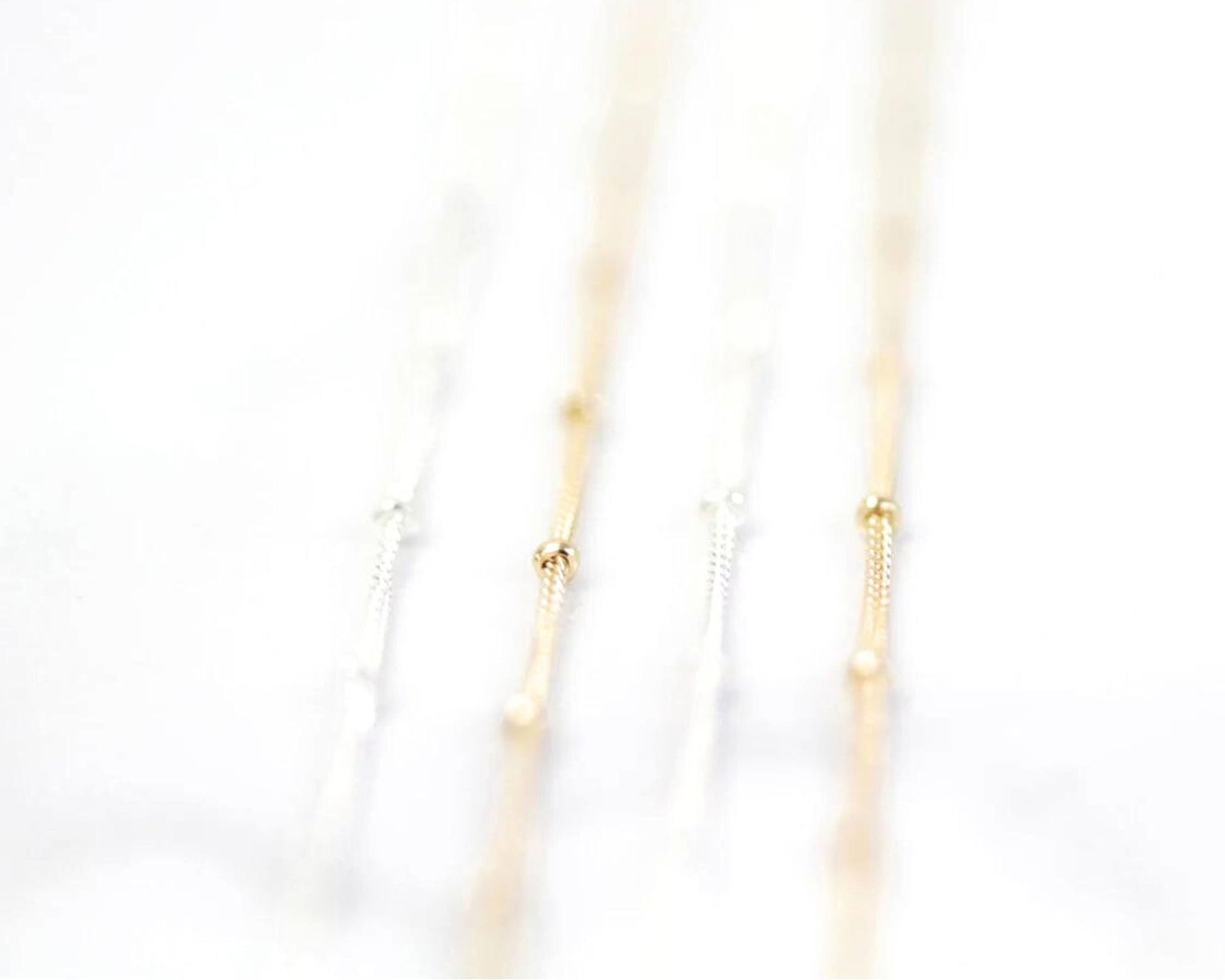 A close-up view of a delicate chain necklace with multiple strands of gold and white beads.
