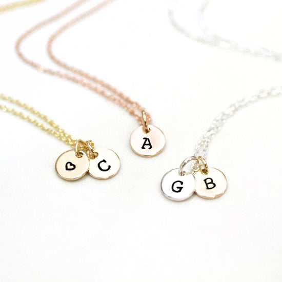 Three personalized necklaces with letters on charms, each charm with a letter and a symbol.
