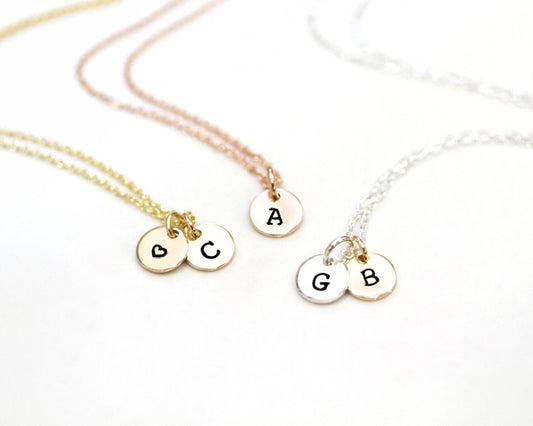Three personalized necklaces with letters on charms, each charm with a letter and a symbol.
