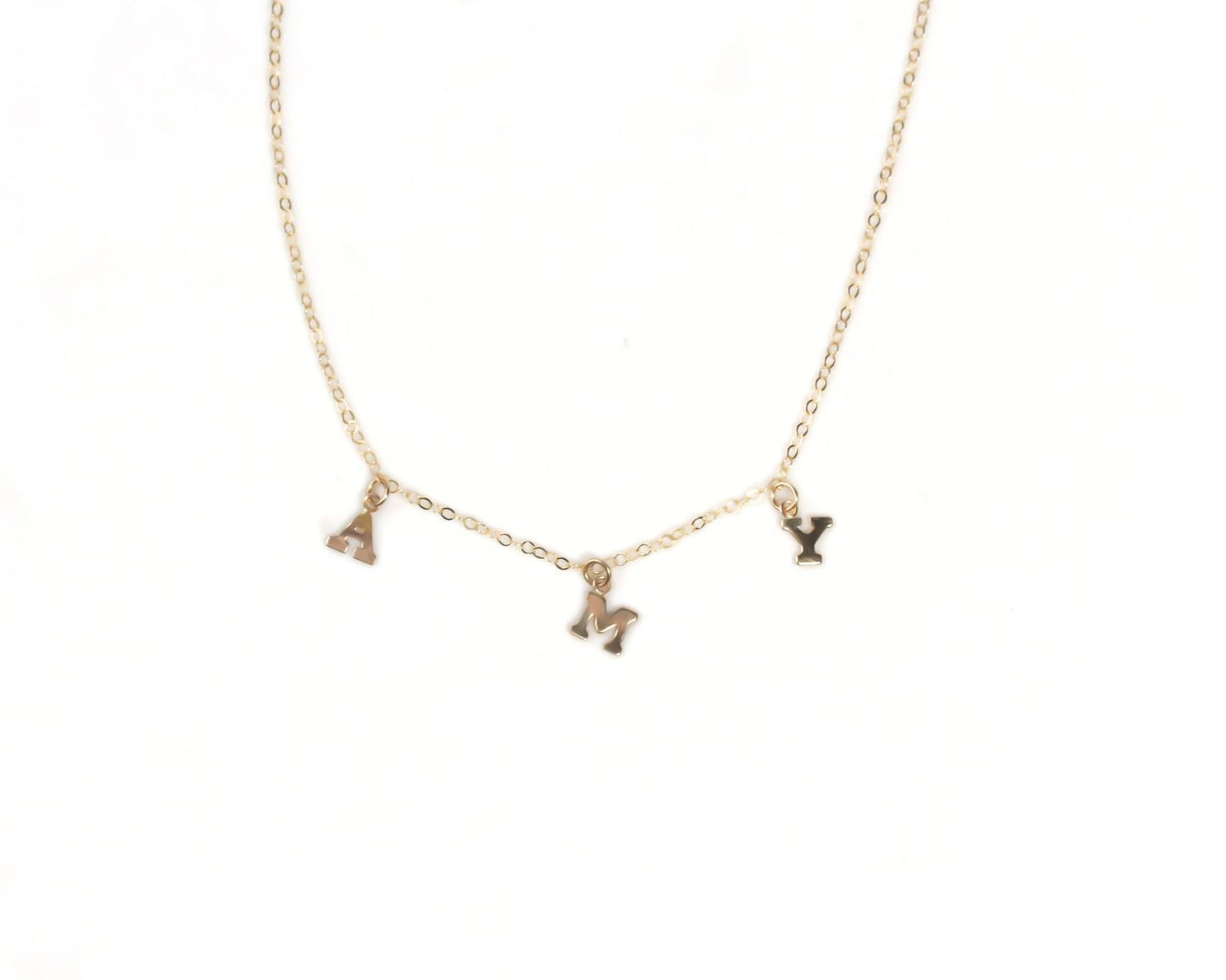 A gold-colored necklace with three small charms hanging from it.