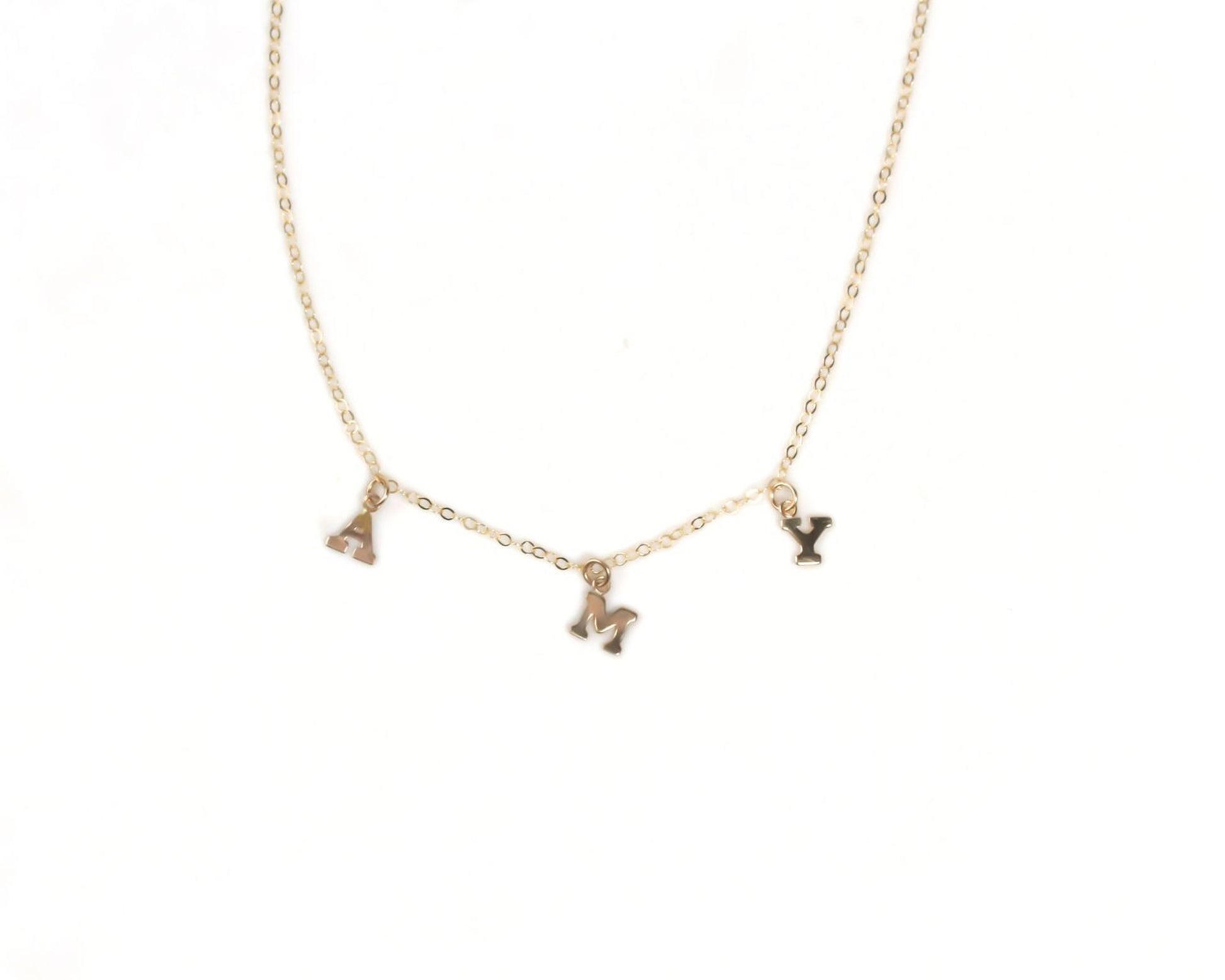 A gold-colored necklace with three small charms hanging from it.