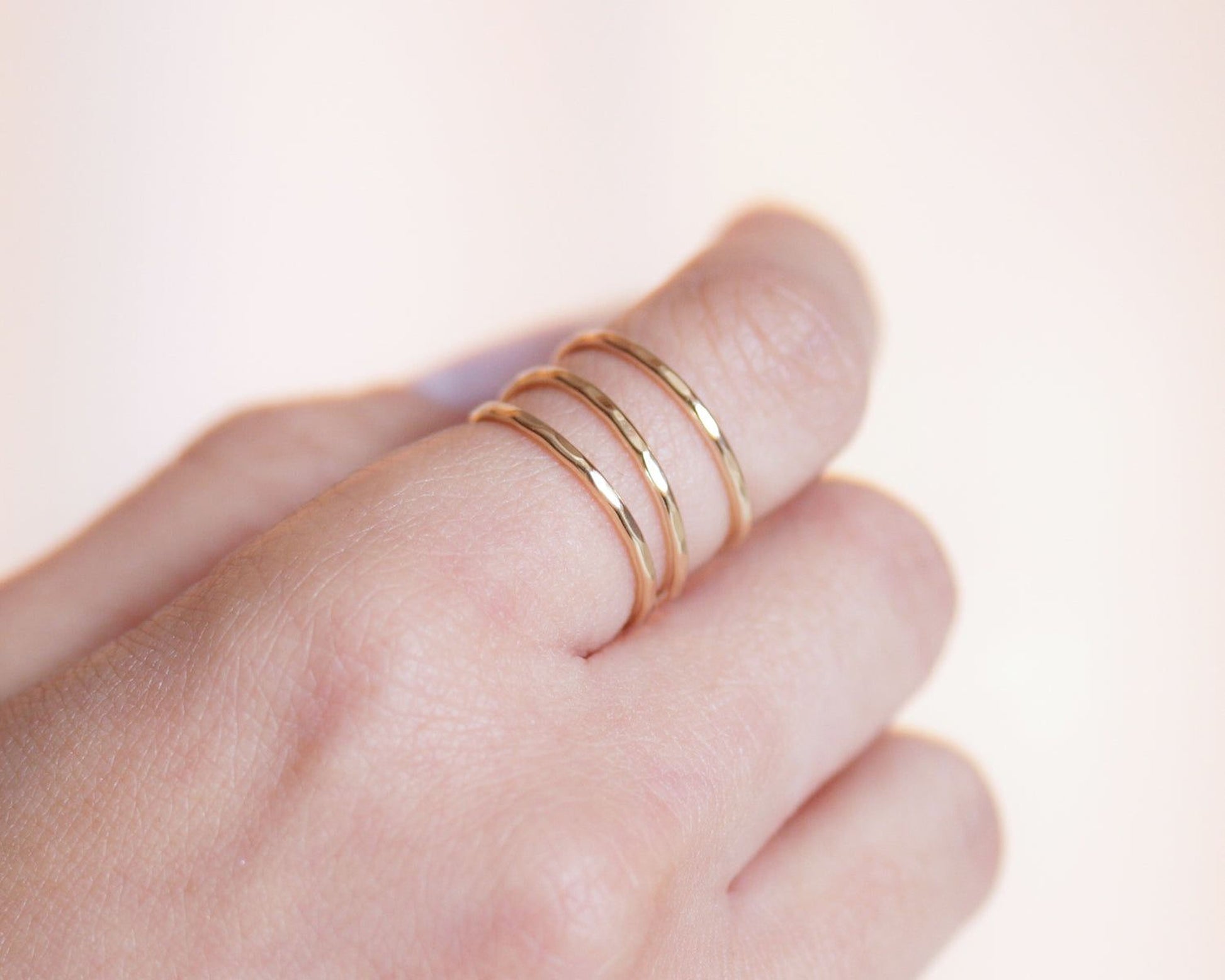 A close-up of a person's hand wearing a gold ring with three concentric rings.