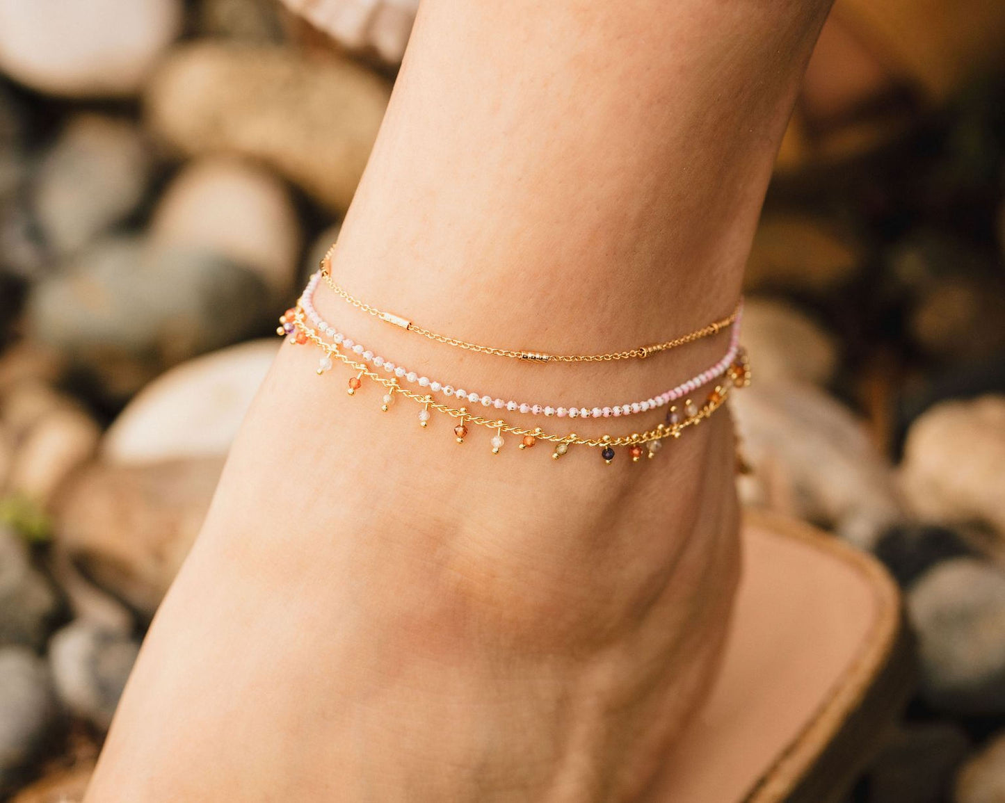 A close-up of a person's ankle wearing a bracelet with multiple strands of beads.