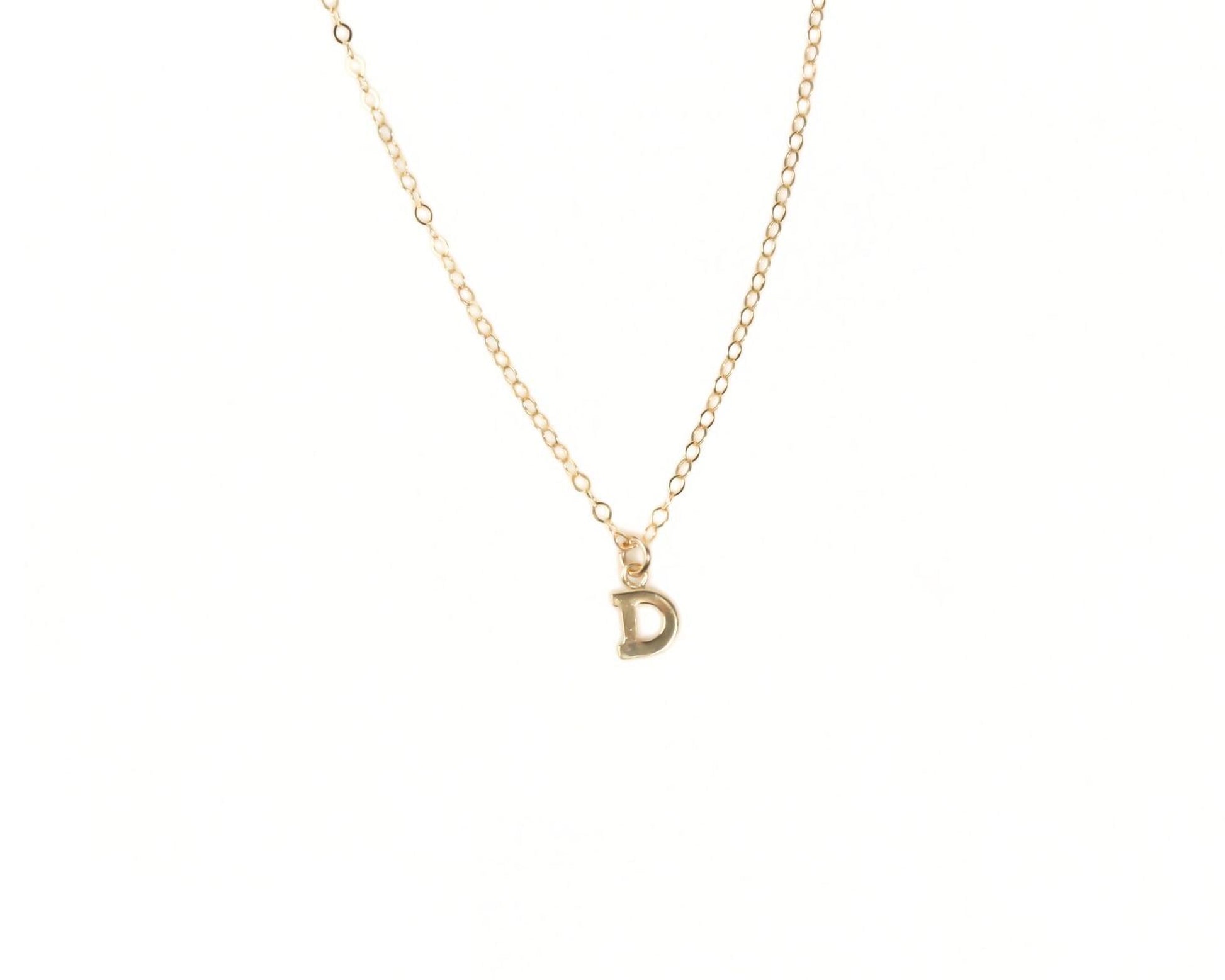 A delicate gold necklace with a single letter pendant.