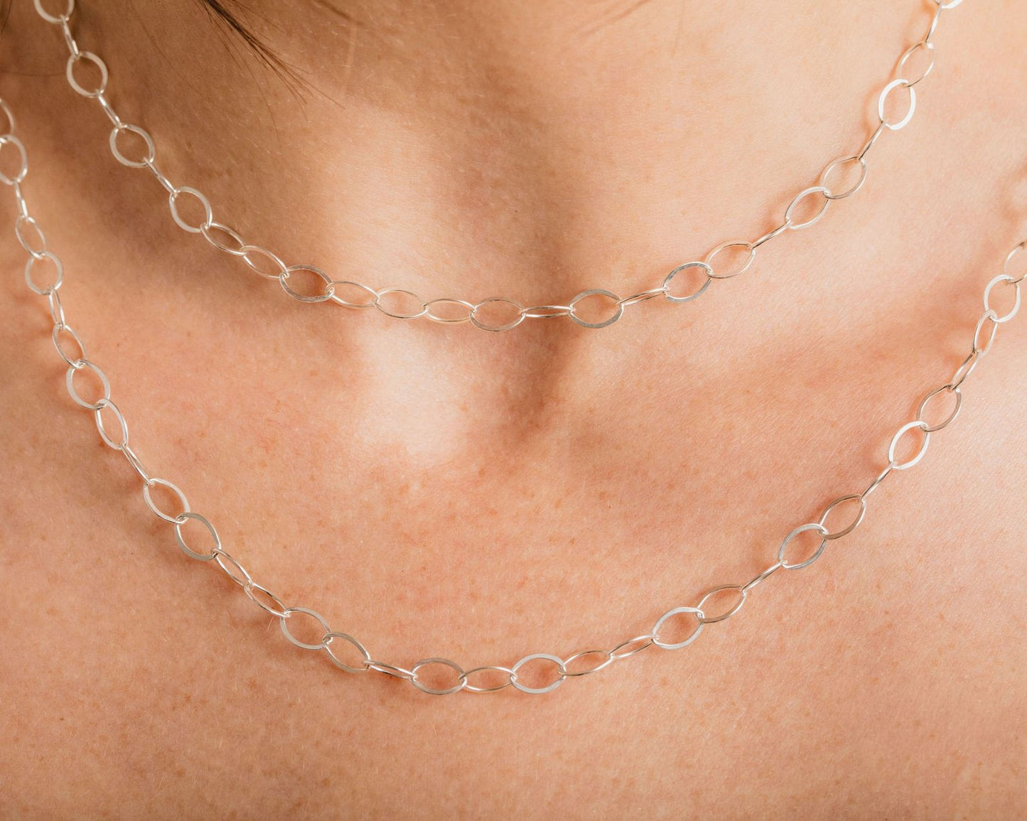 A close-up view of a person's neck and chest area wearing a silver chain necklace.