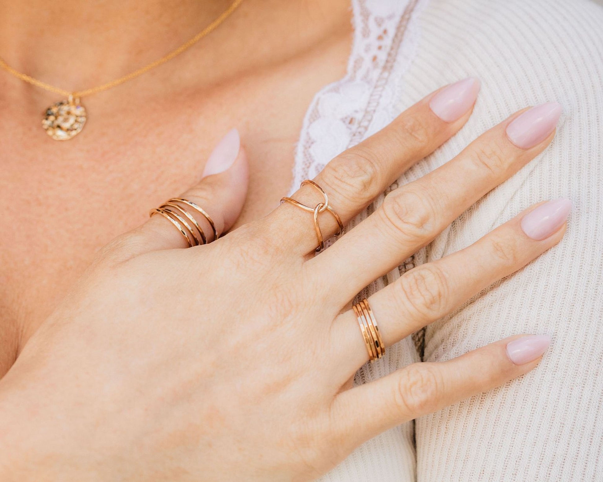 A close-up of a person's hand wearing multiple rings, including a ring with a unique design and another ring with a simple band.