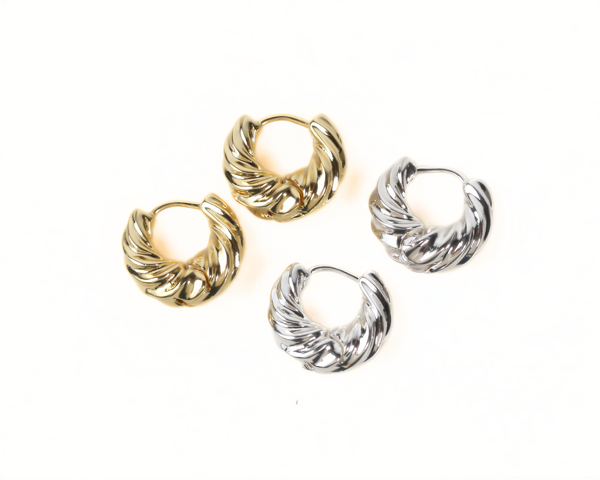 a pair of gold and silver earrings arranged on a white background.