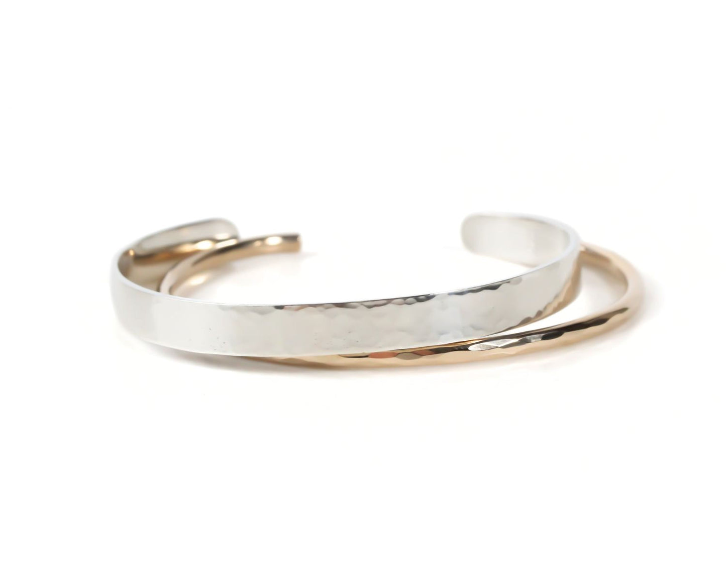 A silver and gold bracelet with a textured surface, resting on a white background.