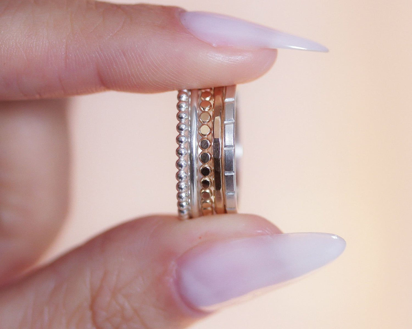A close-up of a person's hand holding a stack of rings, with the rings visible through the fingers.