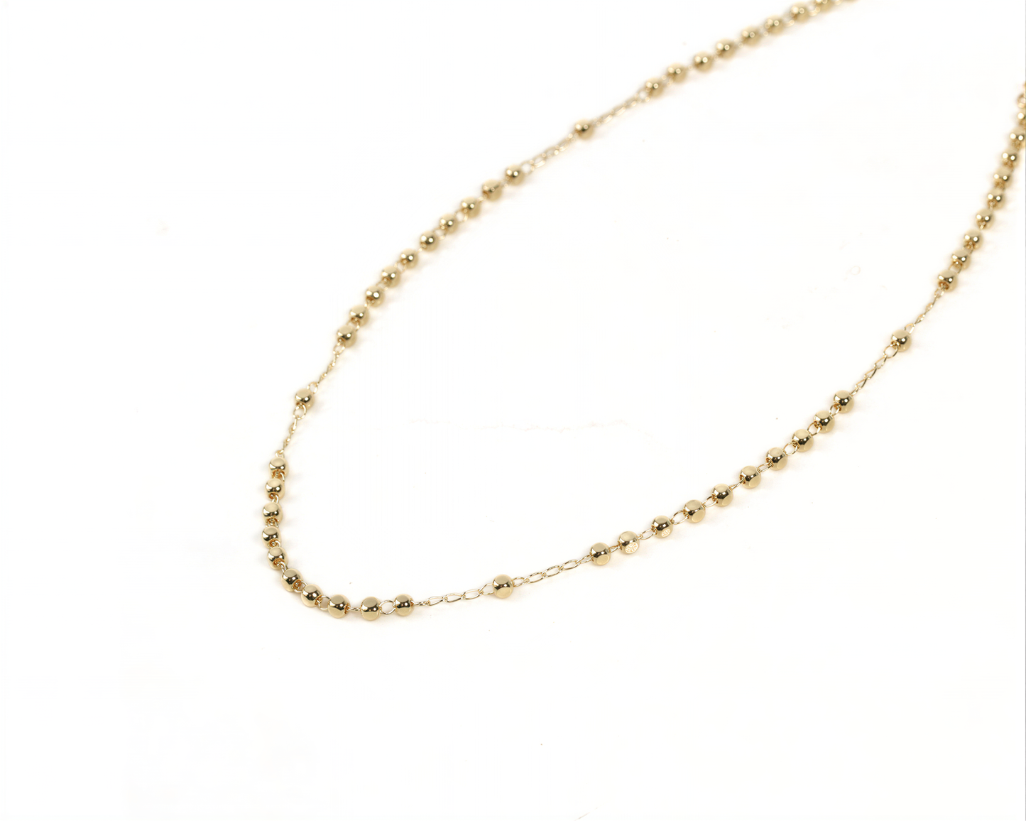 A delicate gold necklace with small, round beads strung together in a delicate pattern.