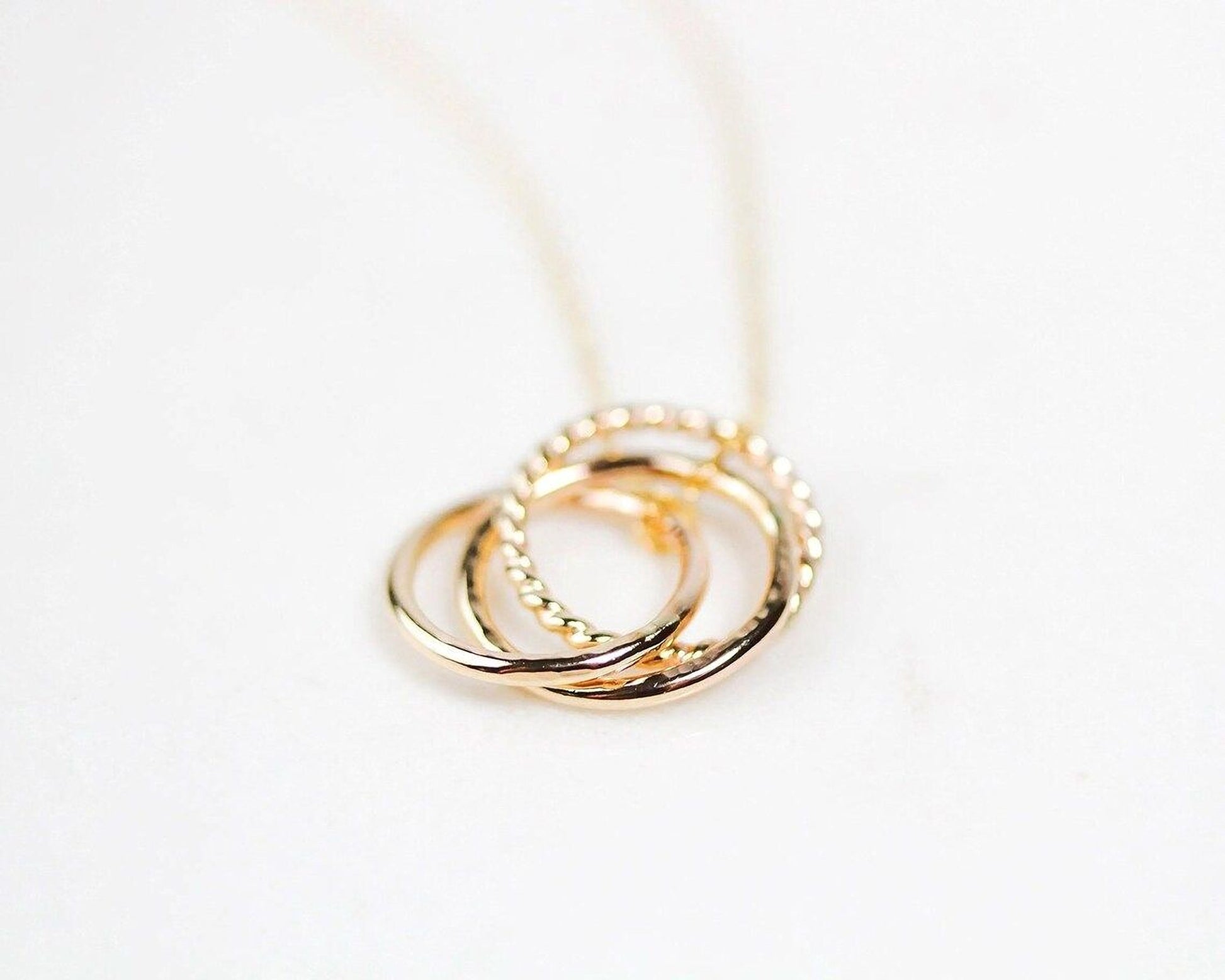 A close-up image of a gold necklace with a pendant in the shape of a ring.