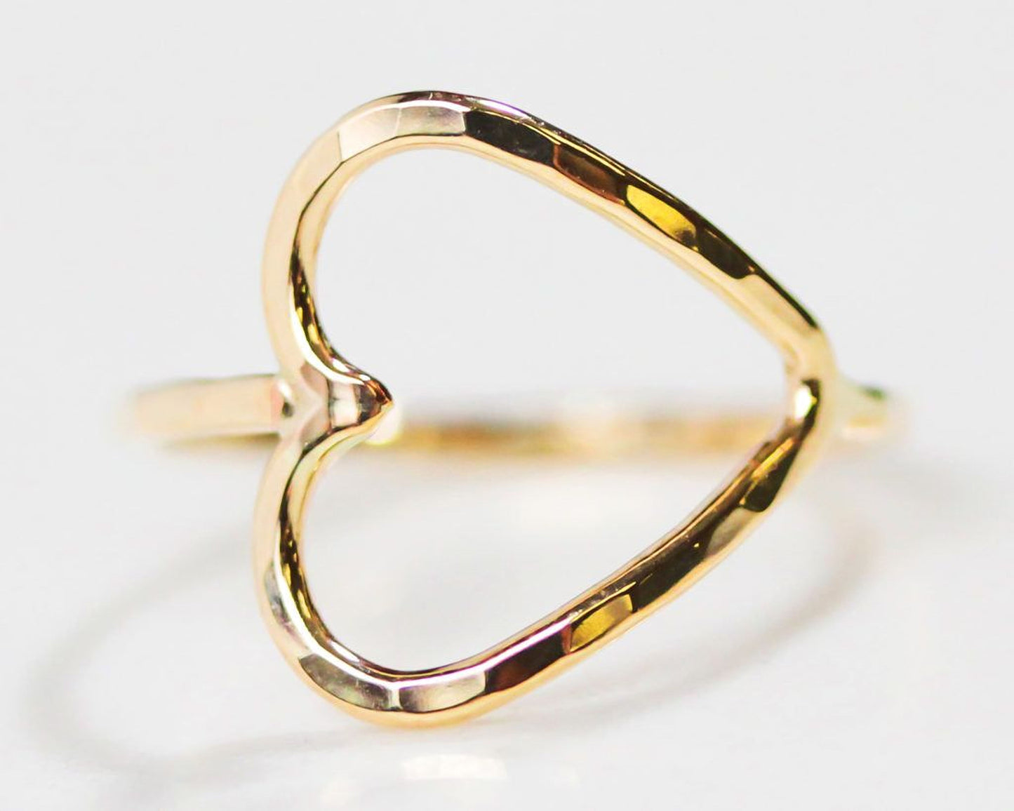 A close-up image of a gold ring with a heart-shaped cutout in the center.