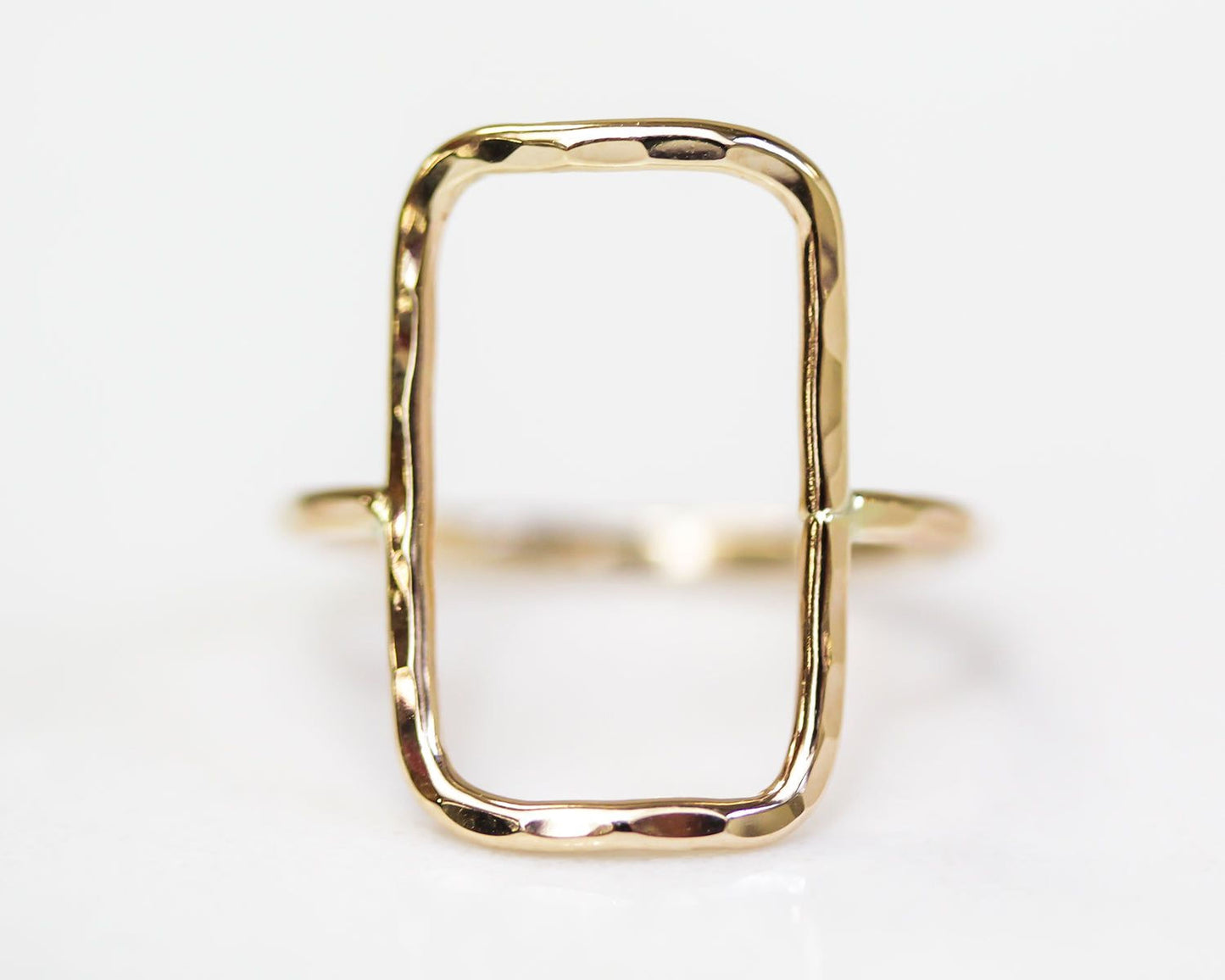 A simple, rectangular-shaped gold ring with a smooth, shiny finish.