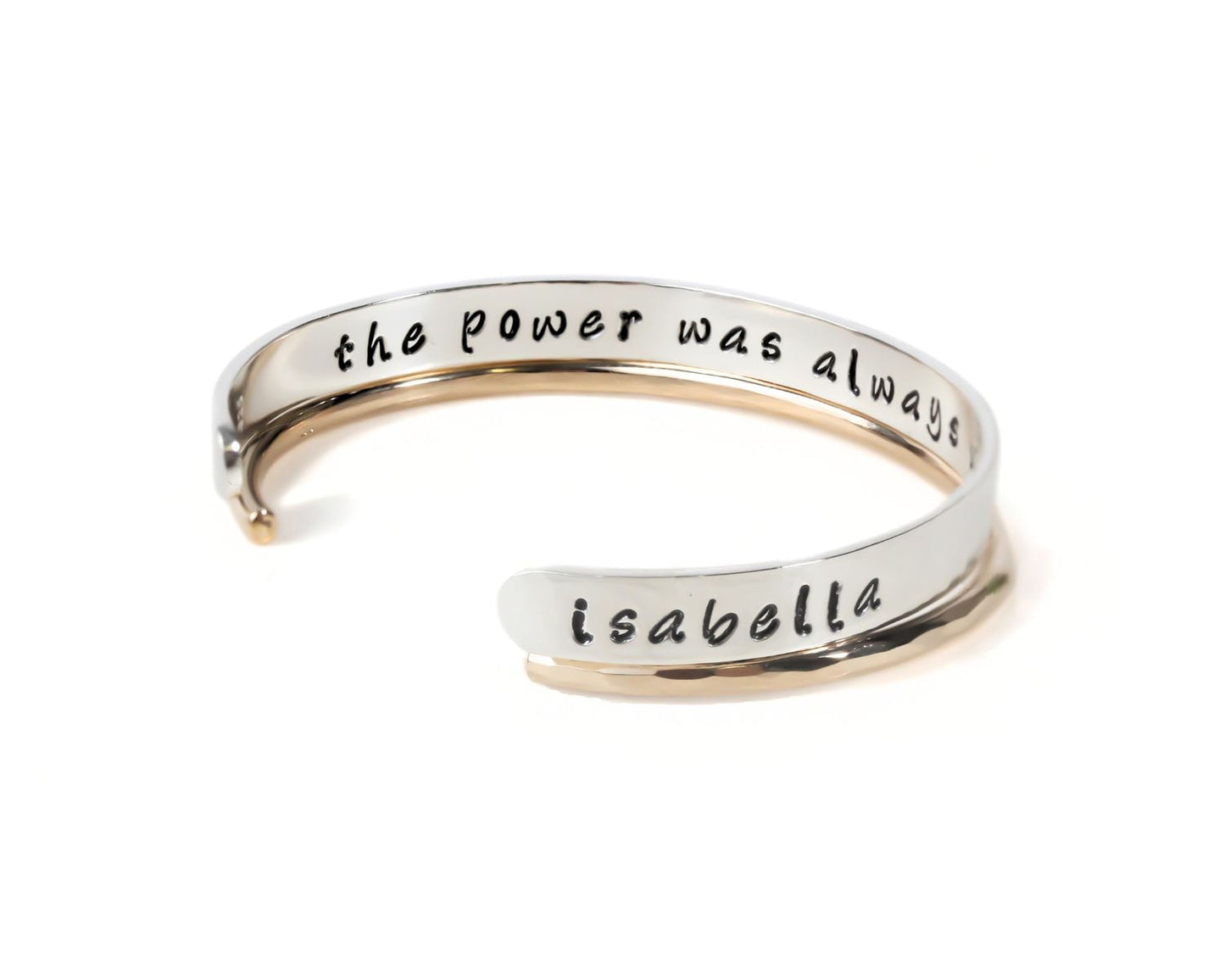 A silver bracelet with the text "the power was always" engraved on it.