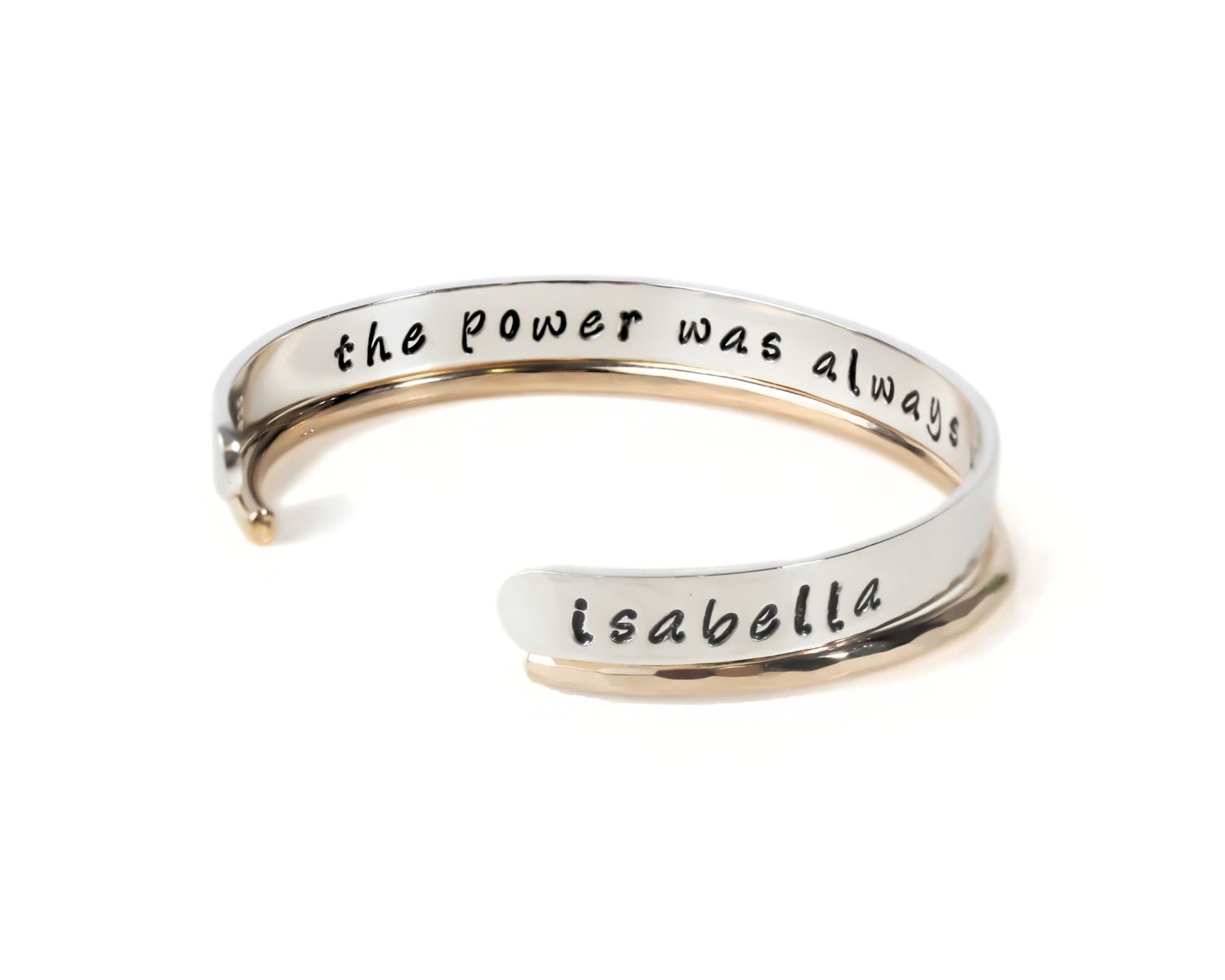 A silver bracelet with the text "the power was always" engraved on it.