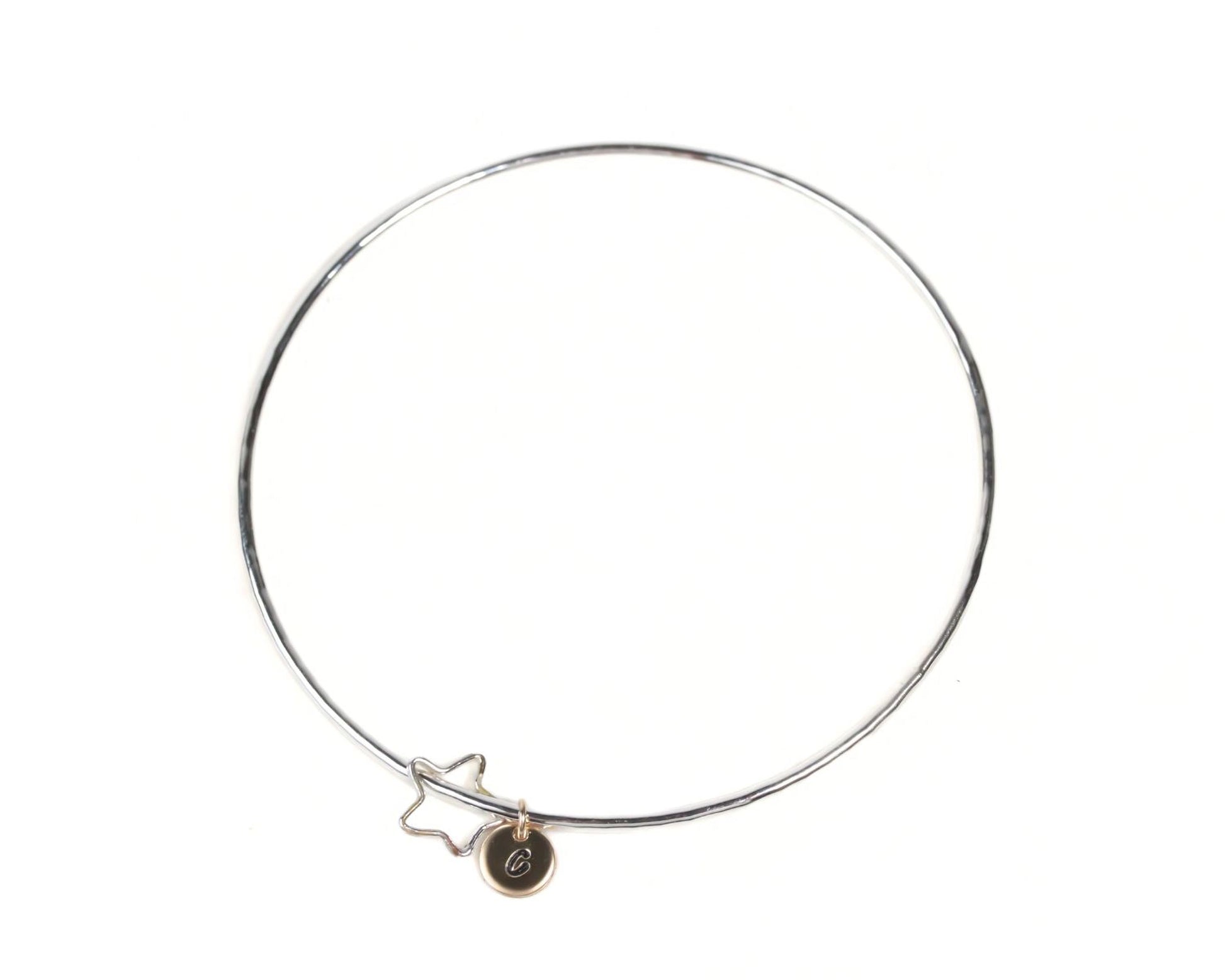 A silver-colored bangle bracelet with a star charm attached to it.