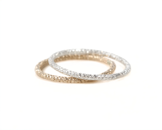 A pair of rings, one gold and one silver, are shown against a white background.