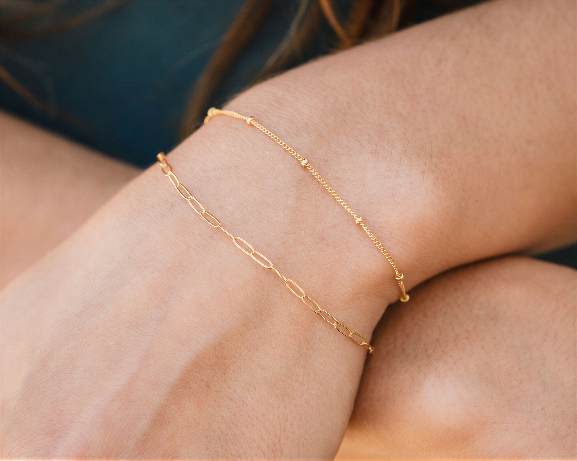 A close-up view of a person's wrist wearing two gold-colored bracelets.