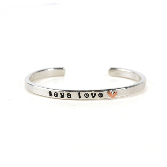 A silver bracelet with the text "toya love" engraved on it.