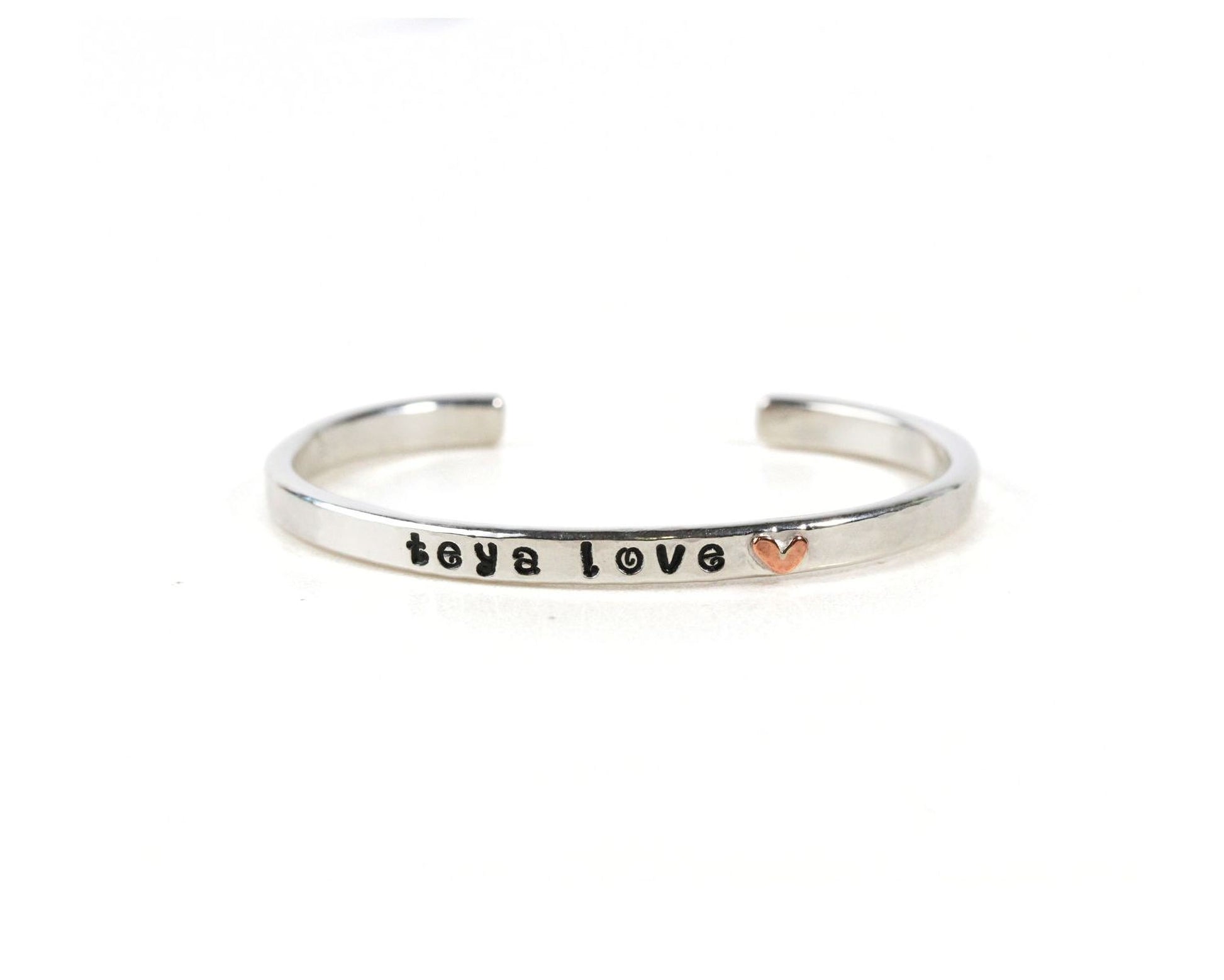 A silver bracelet with the text "toya love" engraved on it.