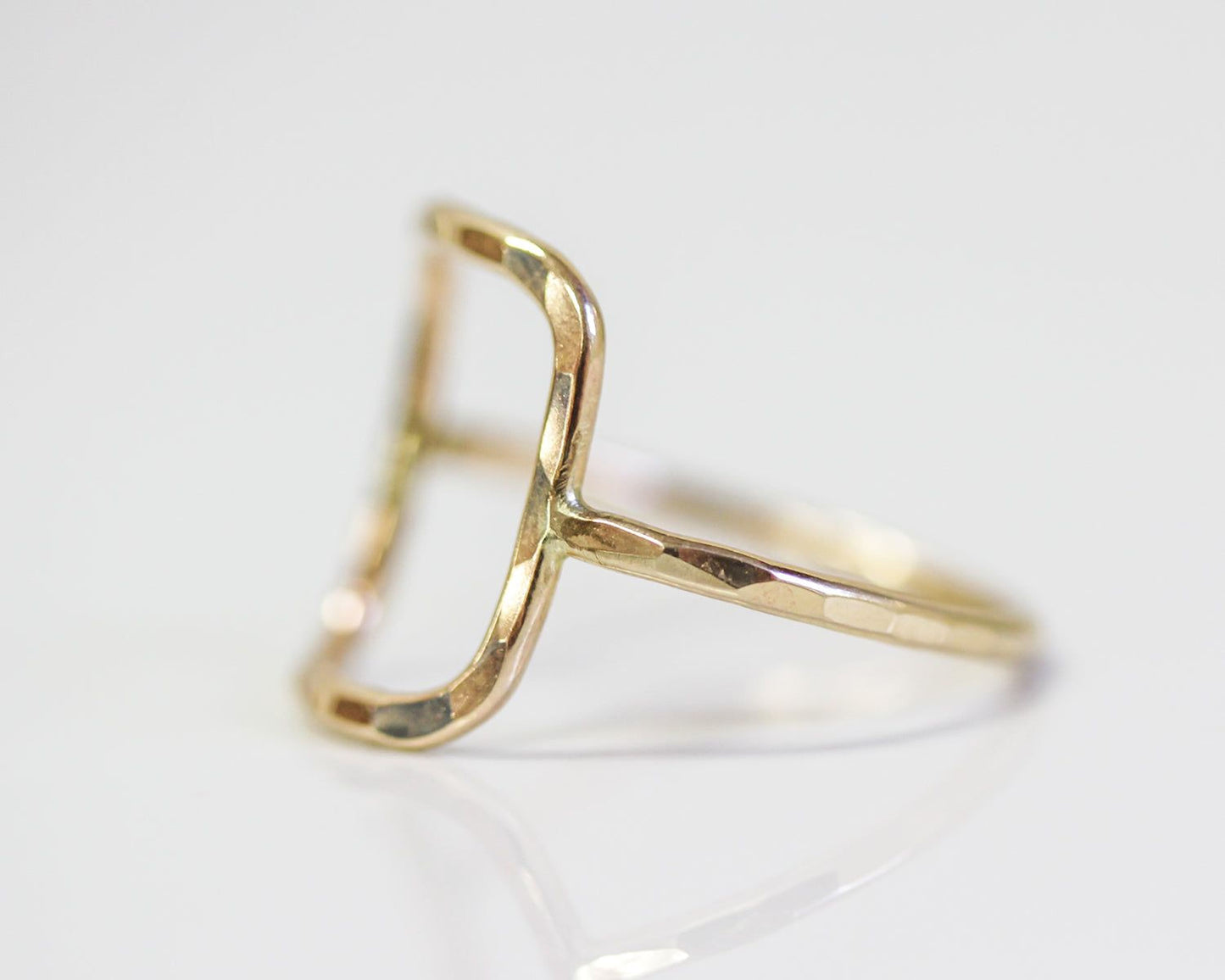 A gold ring with a unique, irregularly shaped design.