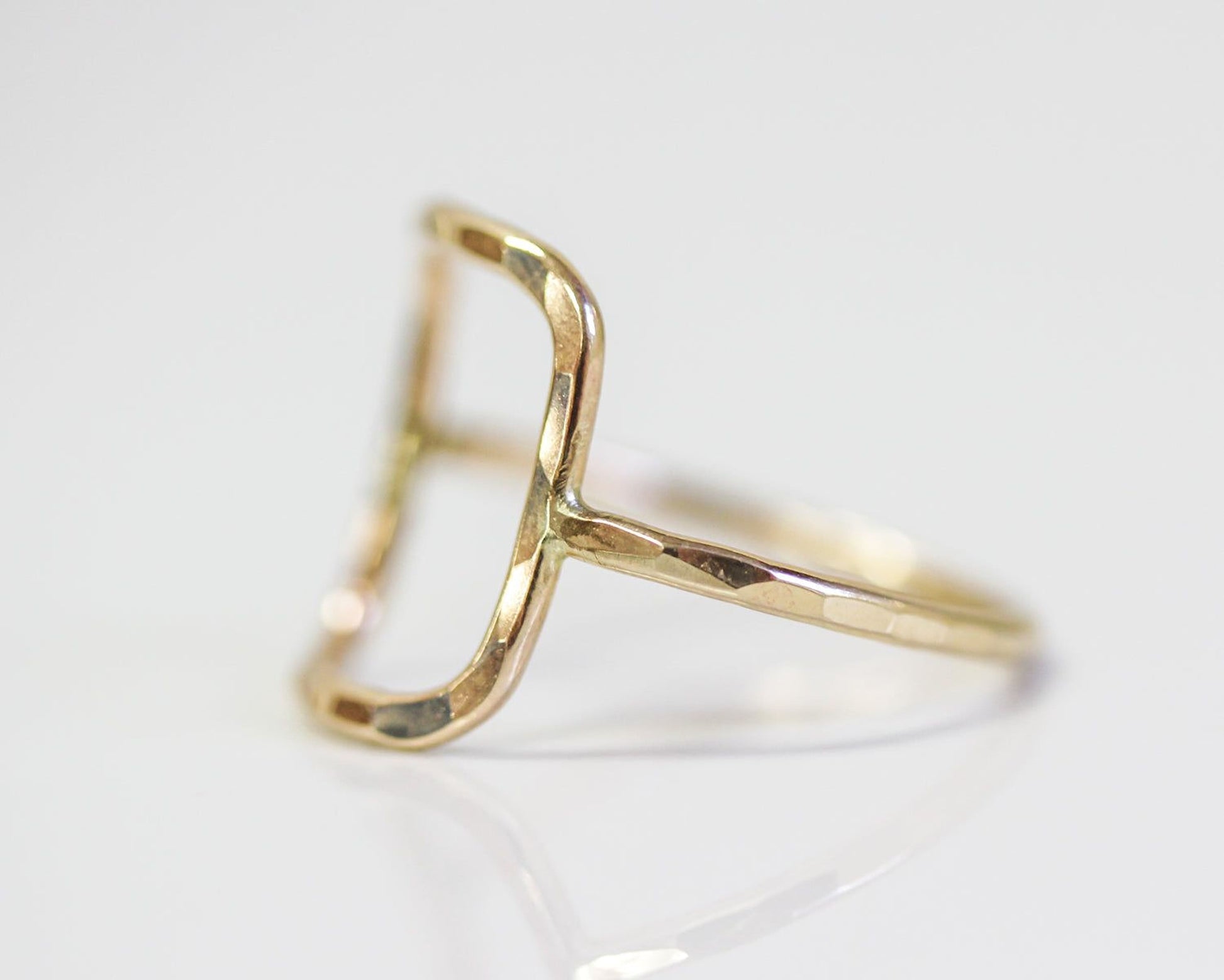 A gold ring with a unique, irregularly shaped design.