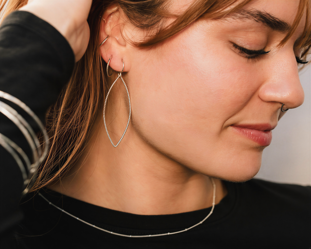 A close-up of a woman's face wearing large hoop earrings and a necklace.