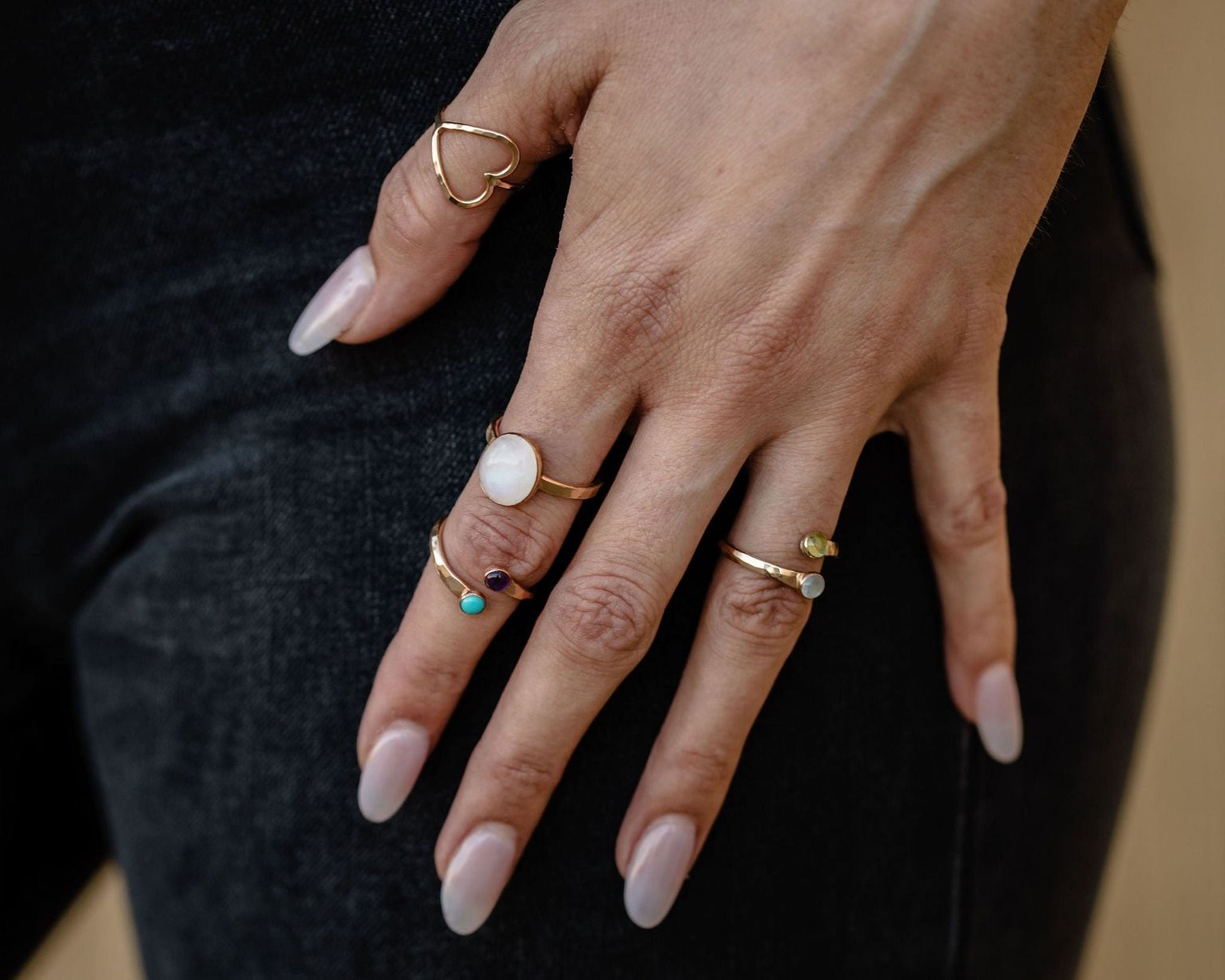 A close-up of a person's hand wearing multiple rings on their fingers.