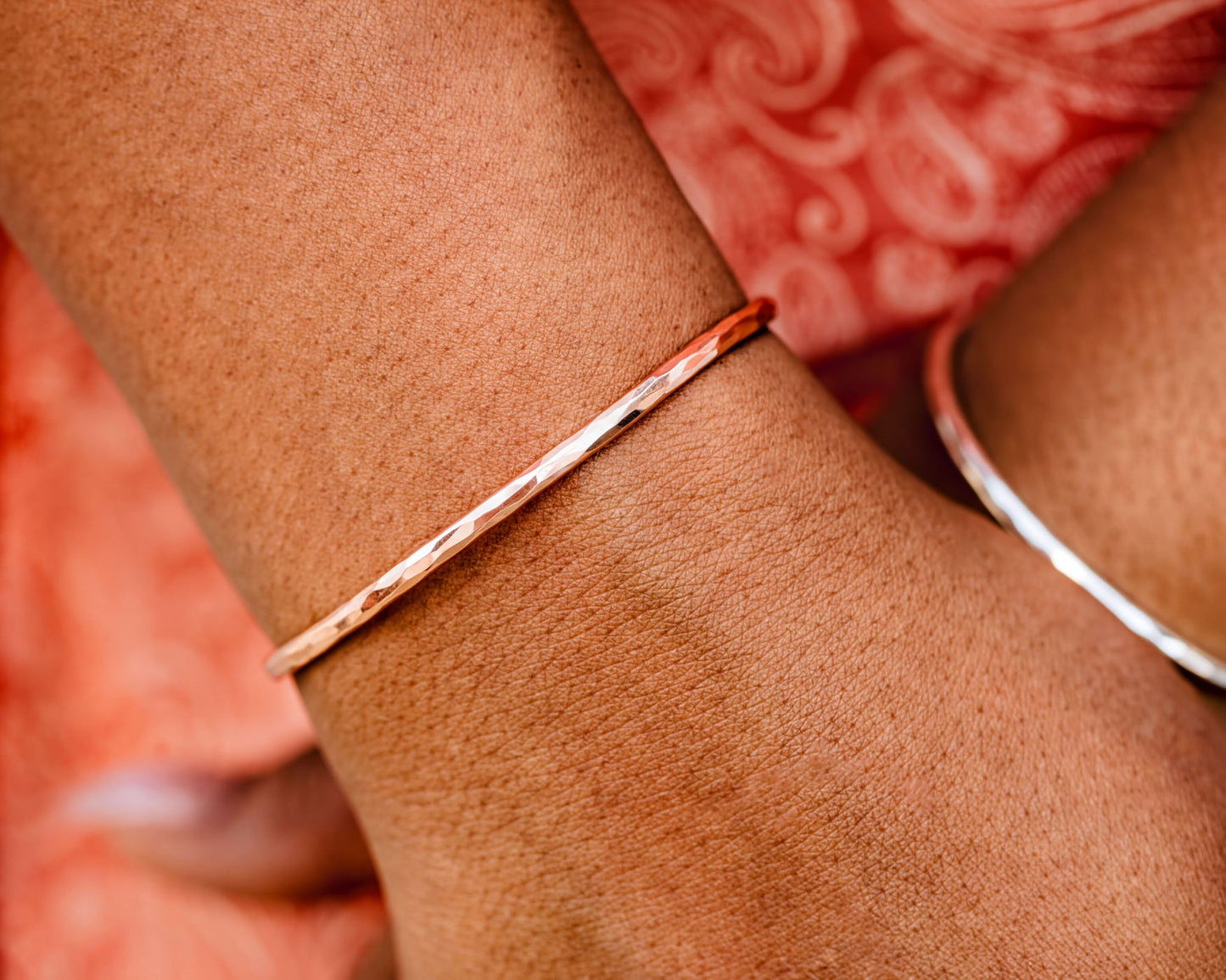 A close-up view of a person's wrist wearing a thin, metallic bracelet.