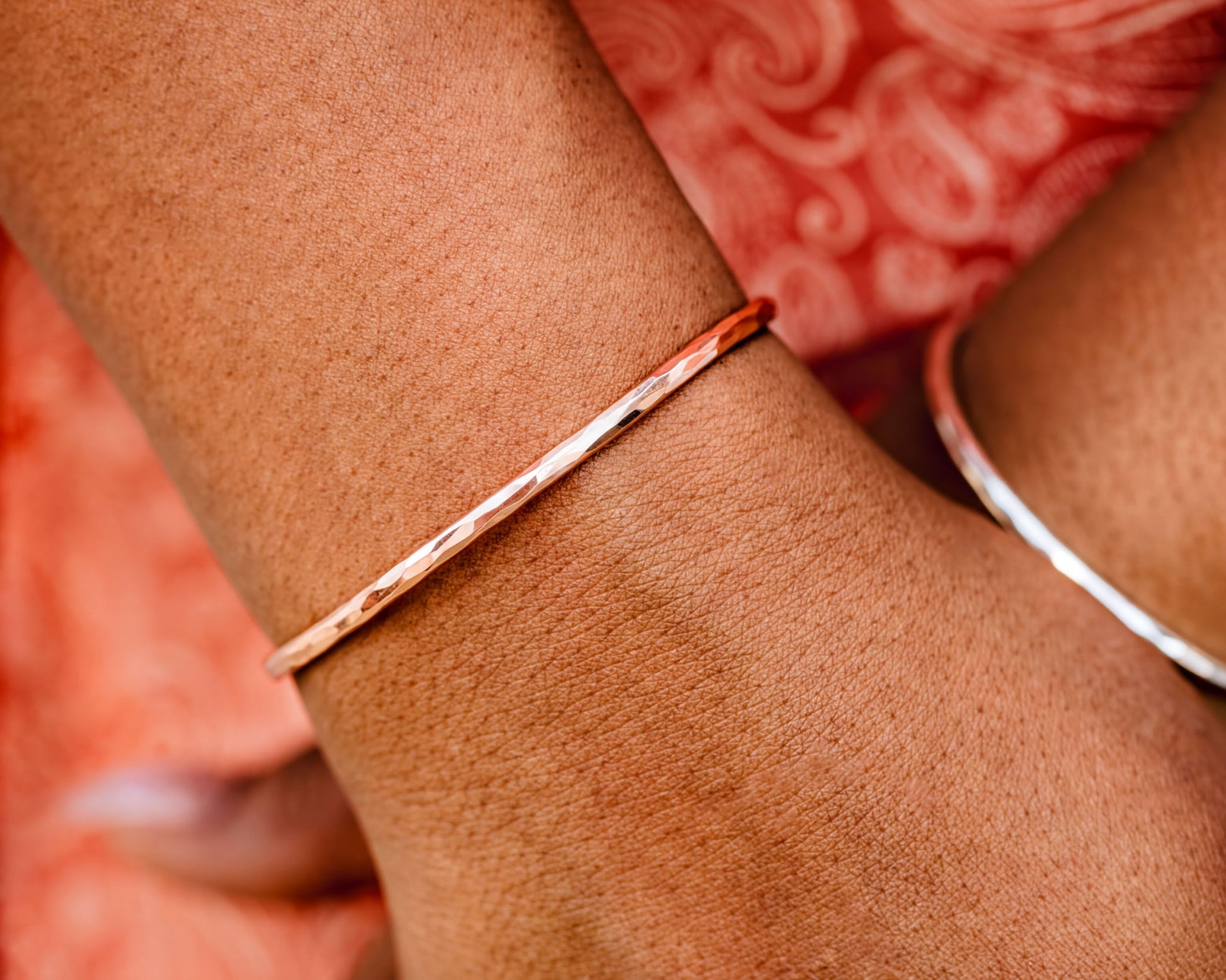 A close-up view of a person's wrist wearing a thin, metallic bracelet.