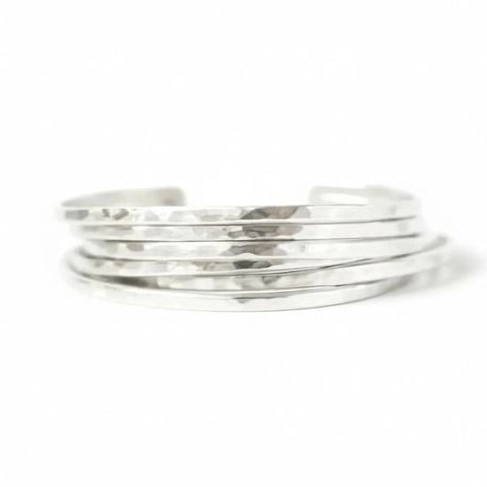 A stack of silver-colored bracelets against a white background.