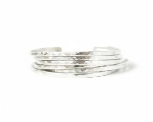 A stack of silver-colored bracelets against a white background.