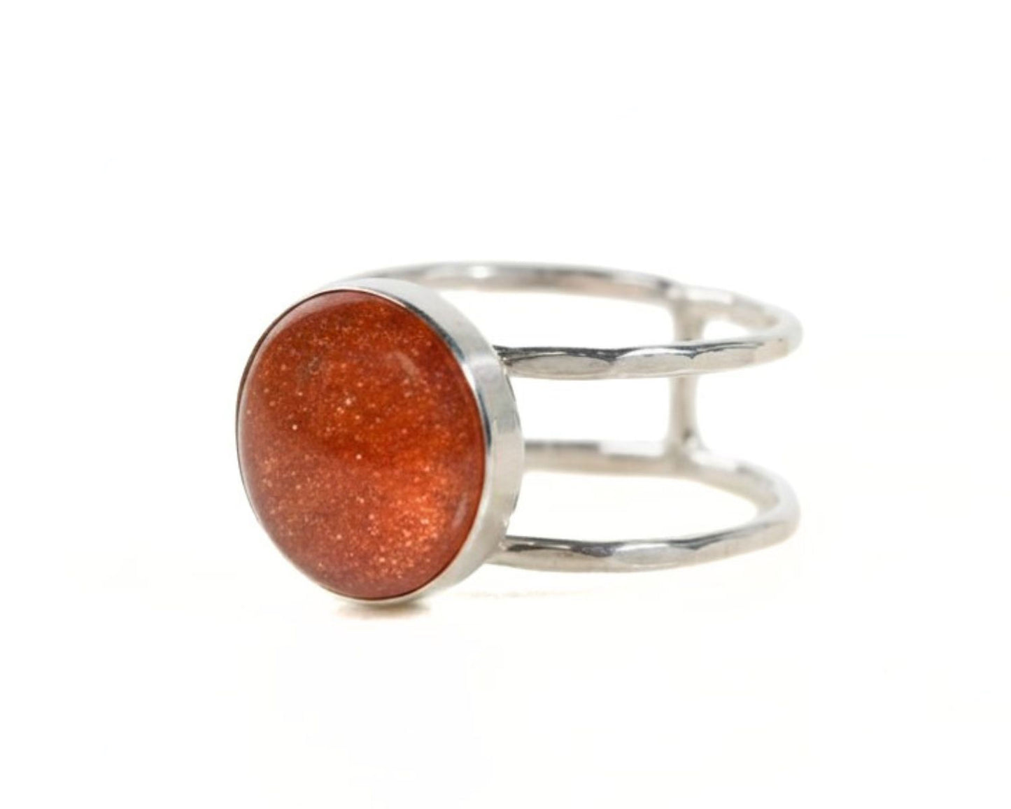 A silver ring with a large, round, orange-colored stone or gemstone in the center.
