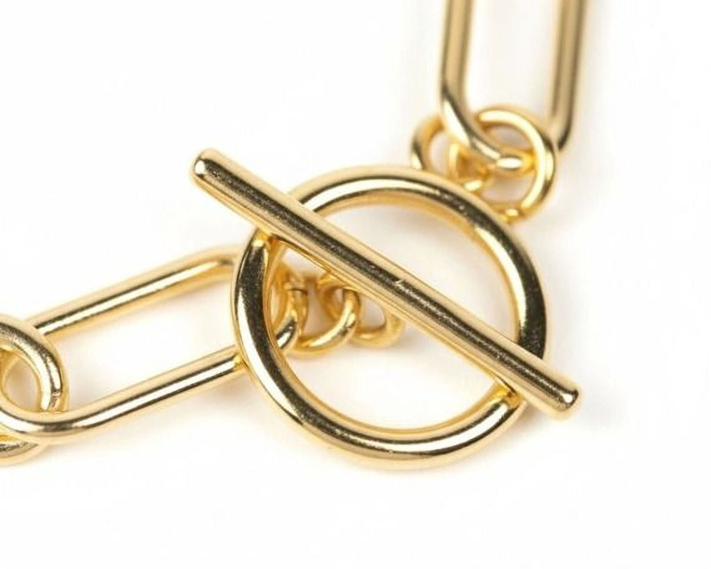 A close-up view of a gold-colored metal chain with a circular clasp and a horizontal bar.