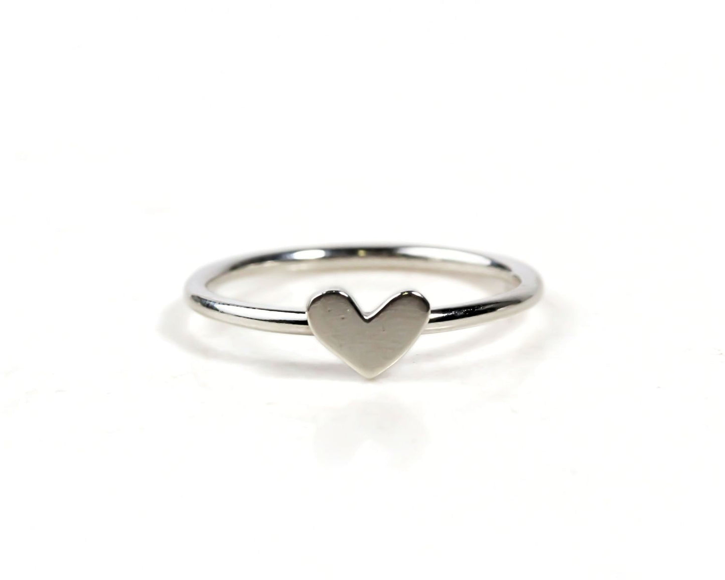 A simple silver ring with a heart-shaped charm in the center.