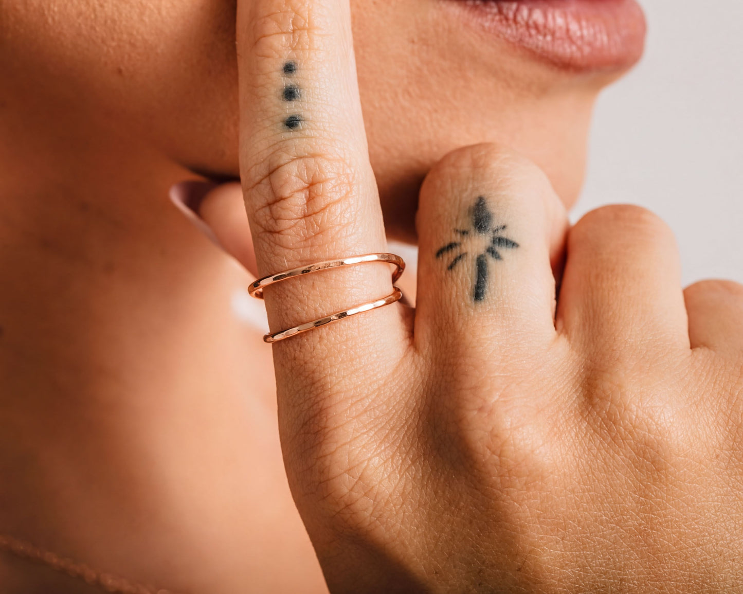 a close-up of a person's hand with a tattoo on the index finger and a ring on the ring finger.