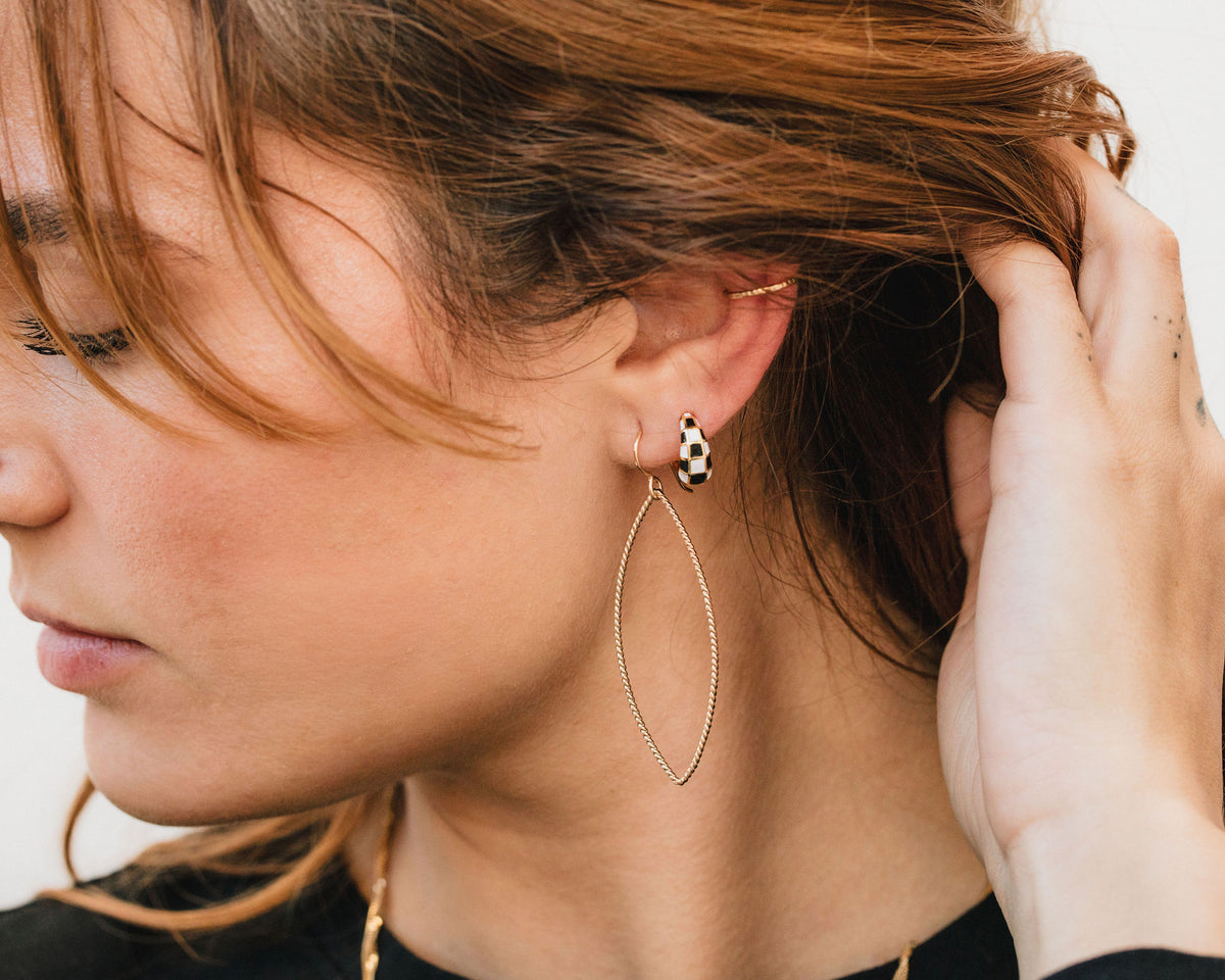 A close-up of a woman's face, focusing on her earrings and hair.