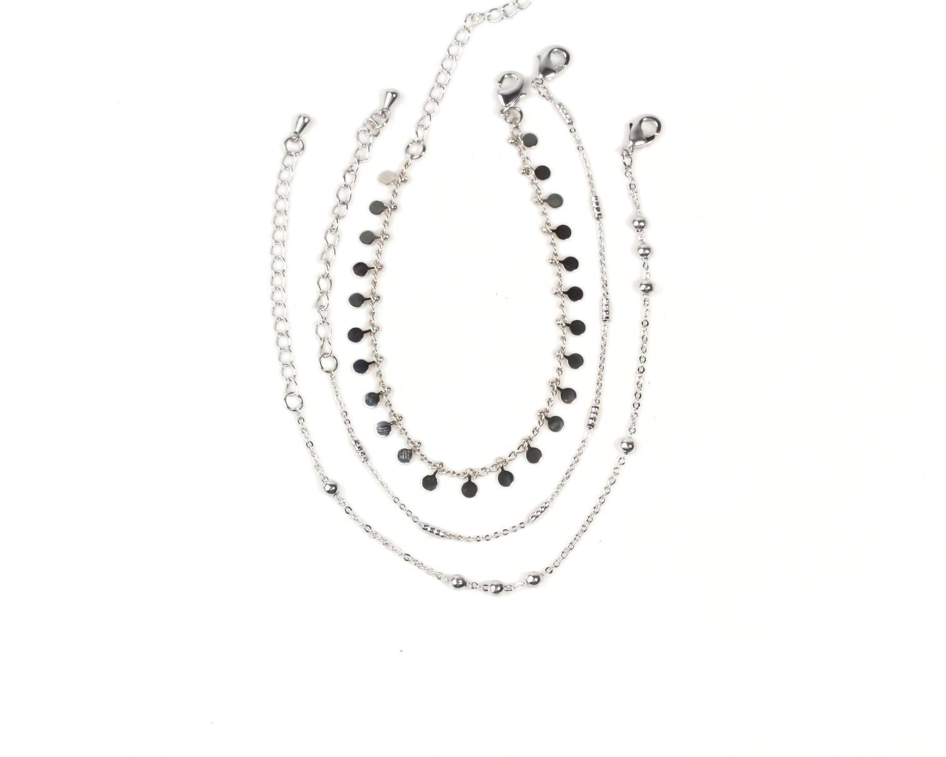 A collection of silver-toned necklaces and bracelets with black circular beads, arranged in a layered fashion.
