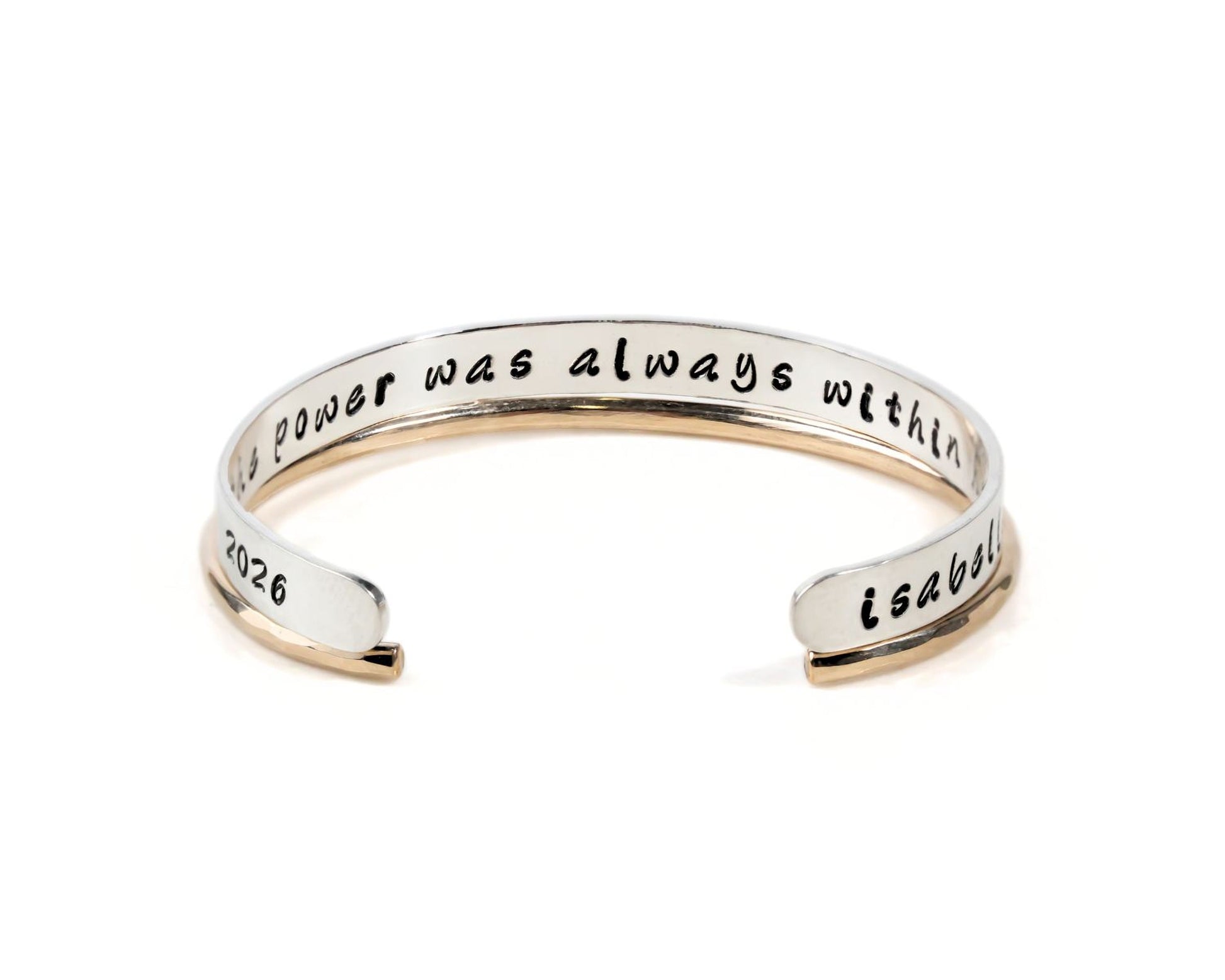 A silver bracelet with the text "The power was always within" engraved on it.
