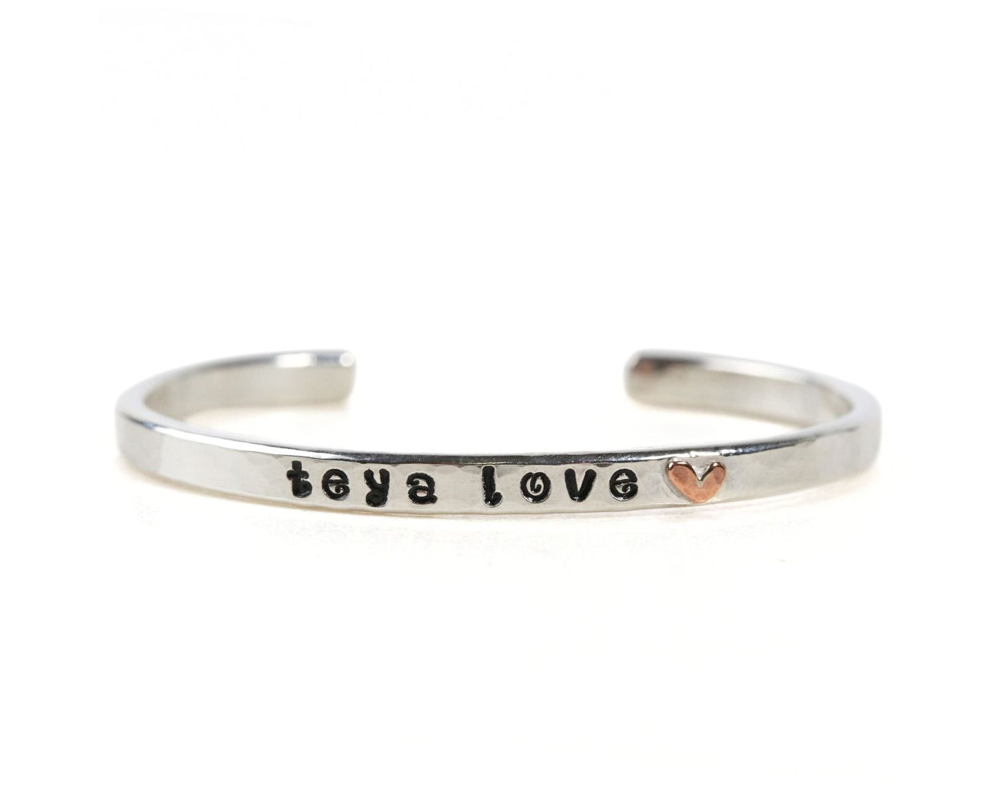 A silver bracelet with the text "taya love" engraved on it.