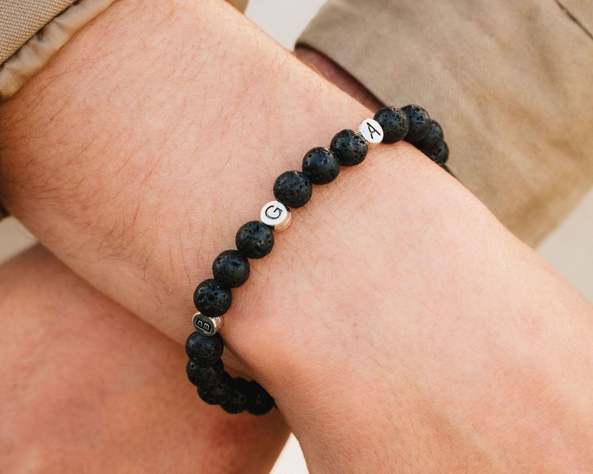 A bracelet made of black beads with letters on them, worn on a person's wrist.
