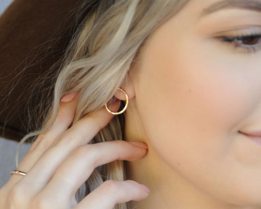 A close-up of a person's face, focusing on their earrings and fingers.