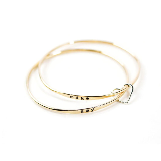 A pair of gold-colored bracelets with the names 'Mike' and 'amy' engraved on them.