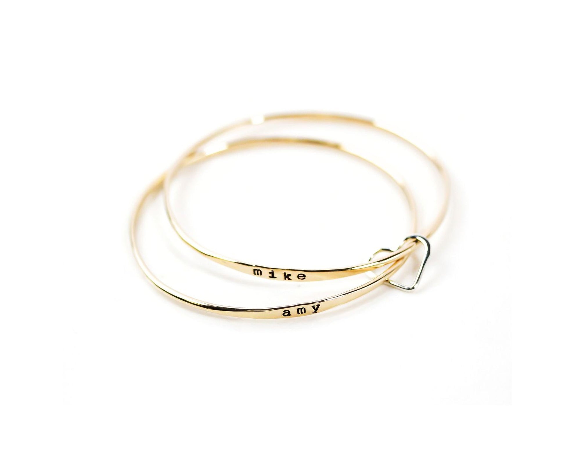 A pair of gold-colored bracelets with the names 'Mike' and 'amy' engraved on them.